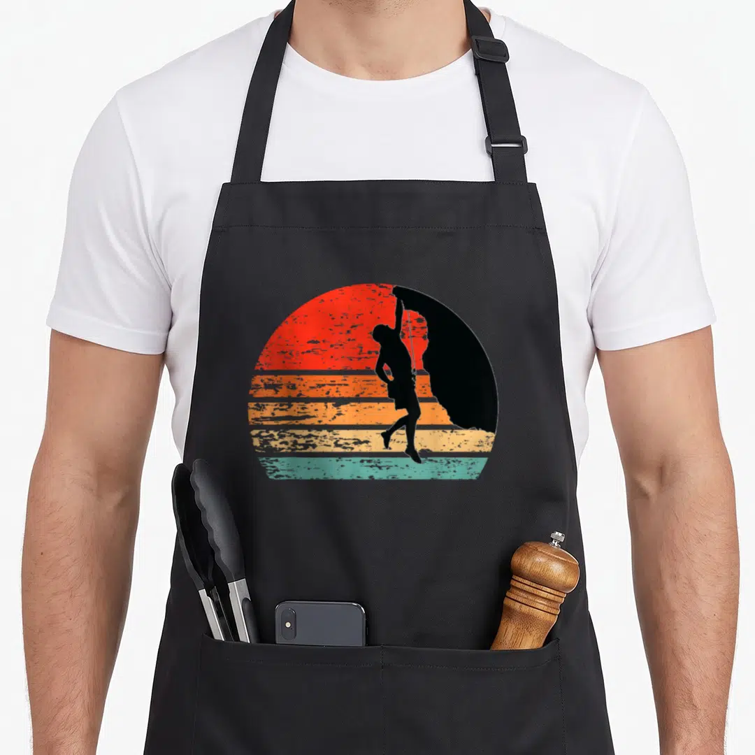 Rock climber apron - Black paraglider silhouette on retro red orange yellow and teal striped sun — shown on a black cotton canvas apron against a white background