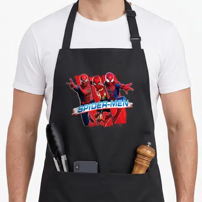 Trio novelty apron - Three Spider-Men in red blue white with SPIDER-MEN banner — shown on a black cotton canvas apron against a white background