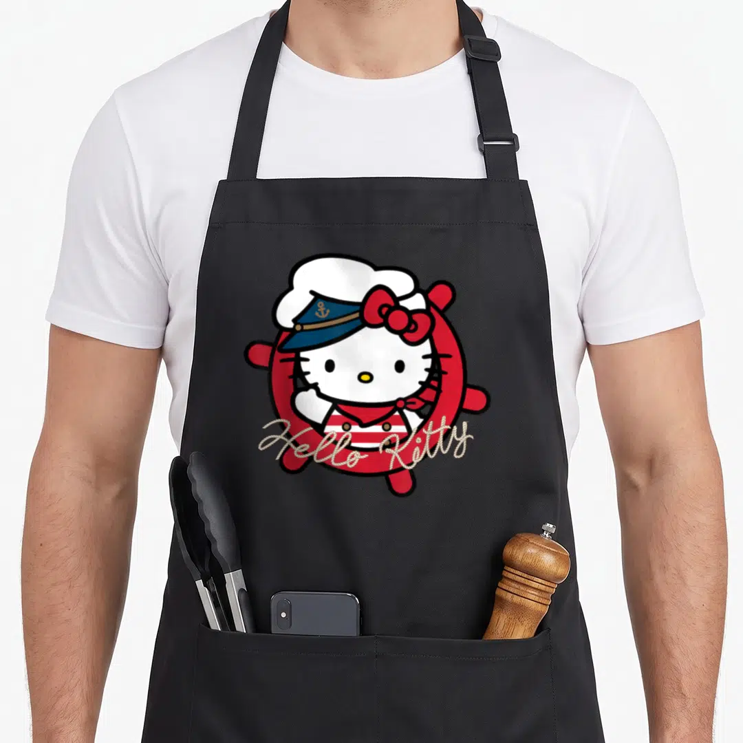 Sailor nautical apron - Hello Kitty in red lifebuoy with blue sailor hat and rope text — shown on a black cotton canvas apron against a white background