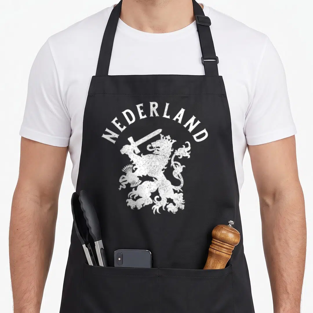 Nederland lion apron - White distressed arched NEDERLAND text over a crowned lion holding a sword — shown on a black cotton canvas apron against a white background