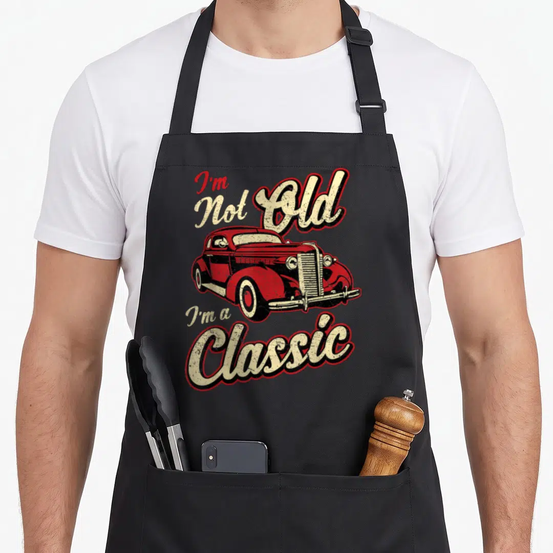 Fan car apron - Red vintage car with I'm Not Old I'm a Classic text in retro style — shown on a black cotton canvas apron against a white background