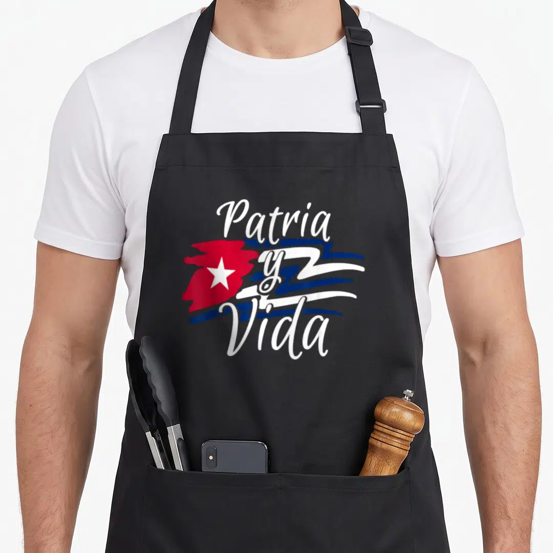 Cuban cuba libre apron - Patria y Vida white script over red island star and blue stripes cartoon art — shown on a black cotton canvas apron against a white background