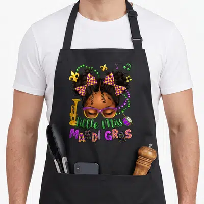Miss new orleans apron - Cartoon girl with purple glasses and checkered bows surrounded by Mardi Gras music notes — shown on a black cotton canvas apron against a white background