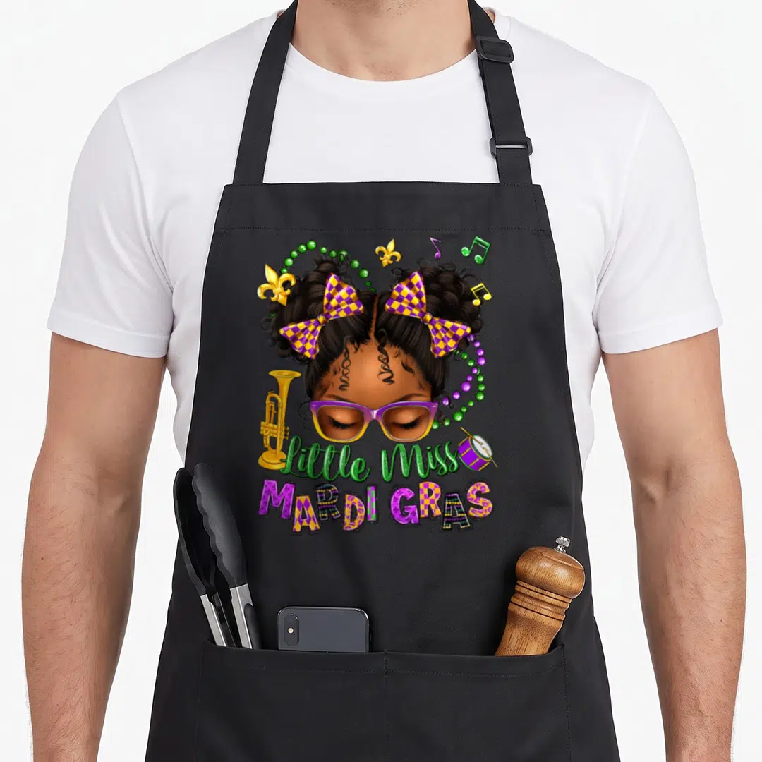 Miss new orleans apron - Cartoon girl with purple glasses and checkered bows surrounded by Mardi Gras music notes — shown on a black cotton canvas apron against a white background