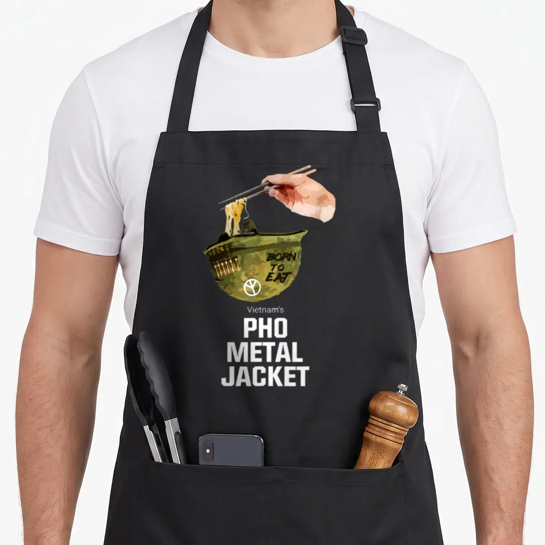 Vietnam pho apron - Camo bowl with chopsticks lifting noodles and Born To Eat Metal Jacket text — shown on a black cotton canvas apron against a white background