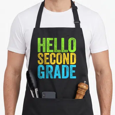 Hello 2nd apron - Stacked HELLO SECOND GRADE text in green yellow blue on black background — shown on a black cotton canvas apron against a white background