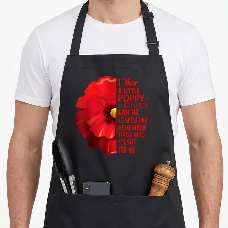 Veteran memorial apron - Red poppy flower next to stacked red text reading I Wear A Little Poppy As Red As Red Can Be — shown on a black cotton canvas apron against a white background