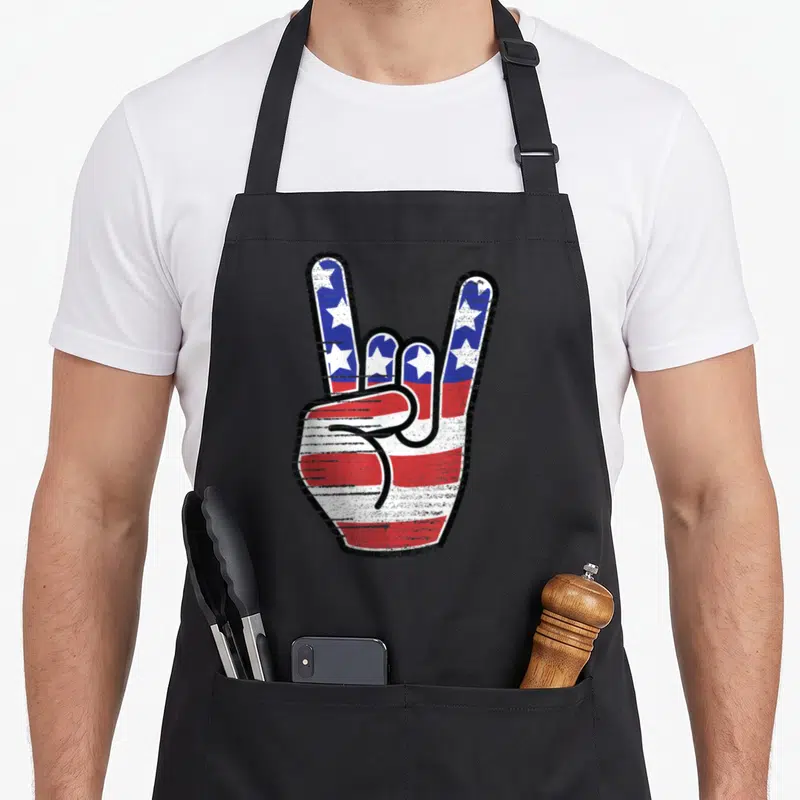 Flag starved rock apron - Distressed rock on hand gesture filled with red white blue stars and stripes pattern — shown on a black cotton canvas apron against a white background