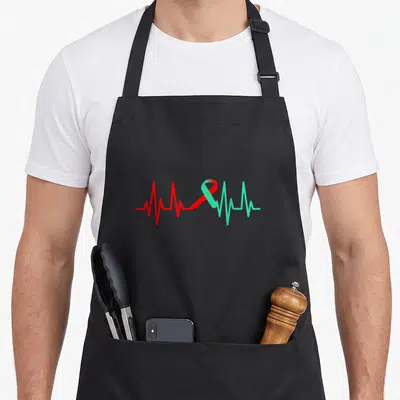 Heartbeat organ apron - Red to green gradient heartbeat line forming an awareness ribbon in a minimalist style — shown on a black cotton canvas apron against a white background