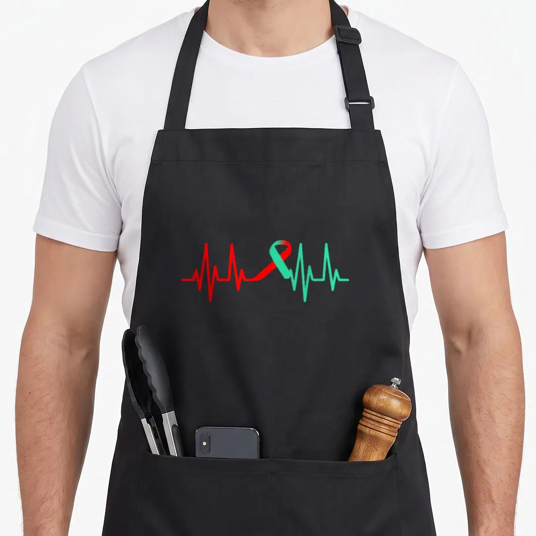 Heartbeat organ apron - Red to green gradient heartbeat line forming an awareness ribbon in a minimalist style — shown on a black cotton canvas apron against a white background