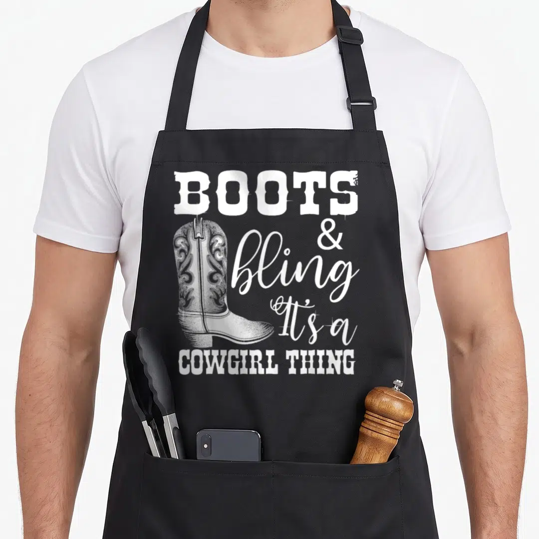 Cowgirl country apron - White cowboy boot with BOOTS & bling It's a COWGIRL THING text in western fonts — shown on a black cotton canvas apron against a white background