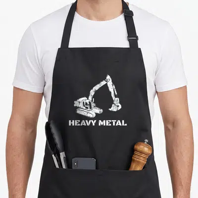 Digger heavy metal apron - Distressed white excavator above HEAVY METAL text — shown on a black cotton canvas apron against a white background