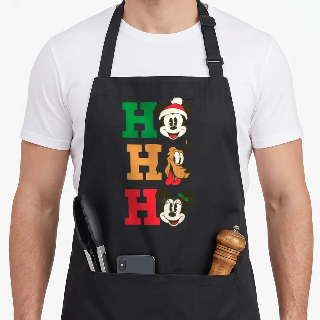 Pluto holiday apron - Three H letters in green orange red paired with Mickey wearing a Santa hat, Pluto, and Minnie — shown on a black cotton canvas apron against a white background