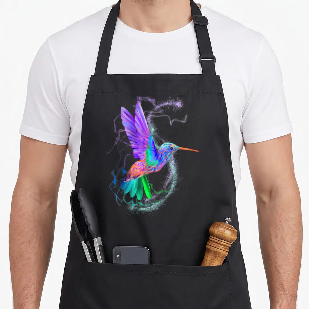 Hummingbird colorful aprons - Multicolored watercolor hummingbird with purple blue green orange swirls and white — shown on a black cotton canvas apron against a white background