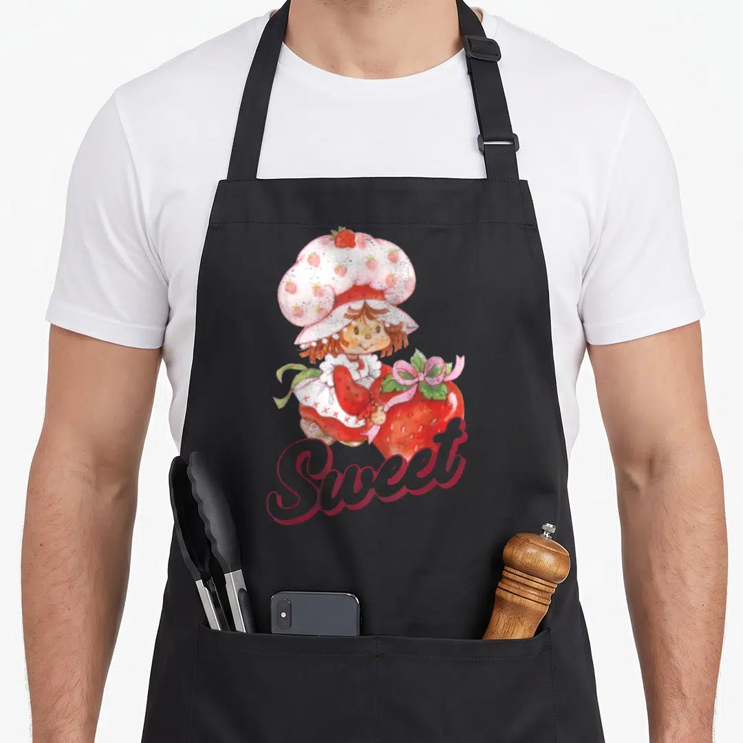 Portrait strawberry apron - Girl holding large red strawberry with Sweet script in watercolor red pink white peach — shown on a black cotton canvas apron against a white background