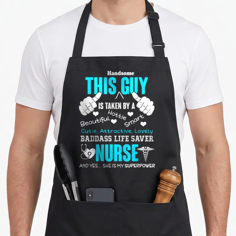 Taken nurse apron - Stacked blue and white text This Guy Is Taken By A Nurse with pointing hands and medical symbols — shown on a black cotton canvas apron against a white background