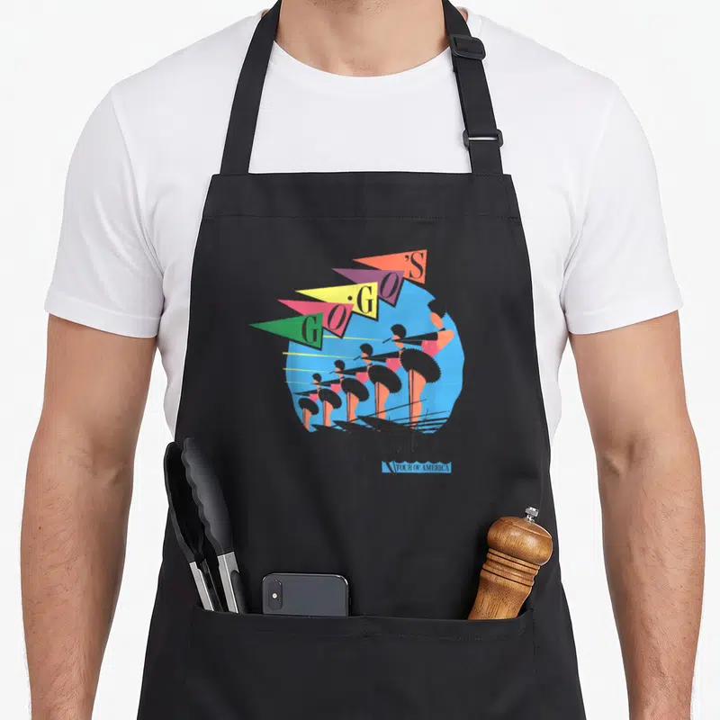 Gos novelty apron - Five dancers in blue circle with GOGO'S Vacation pennants and Tour of America text — shown on a black cotton canvas apron against a white background