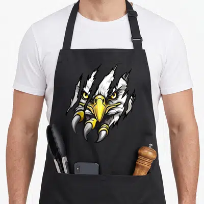 Football eagles apron - Cartoon eagle head tearing through background with three yellow and white talons in black — shown on a black cotton canvas apron against a white background
