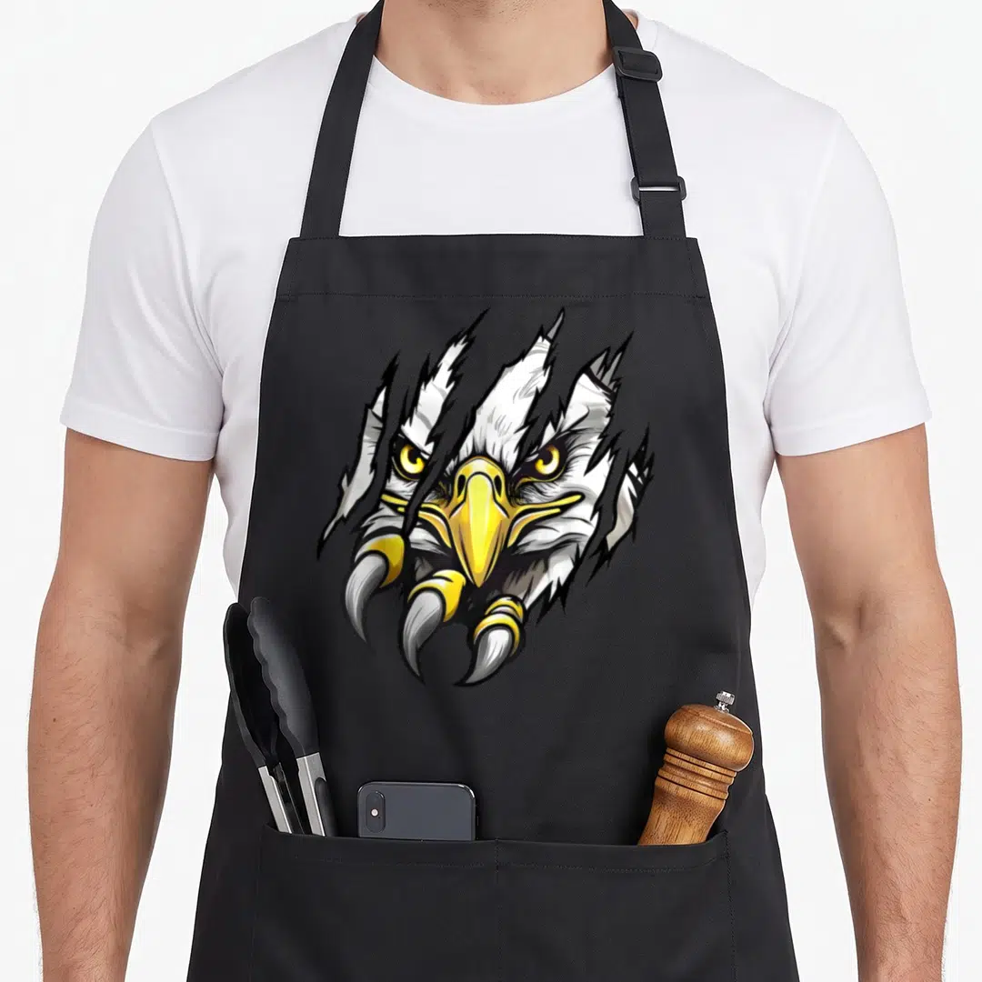 Football eagles apron - Cartoon eagle head tearing through background with three yellow and white talons in black — shown on a black cotton canvas apron against a white background