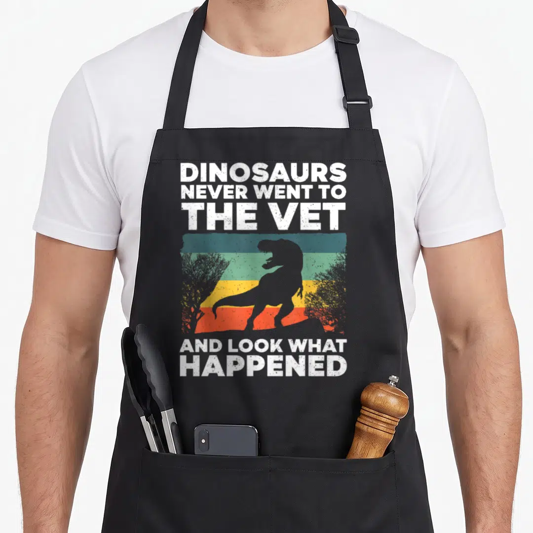 Funny veterinarian veterinary apron - Dinosaur silhouette on colored stripes with text about never going to the vet — shown on a black cotton canvas apron against a white background