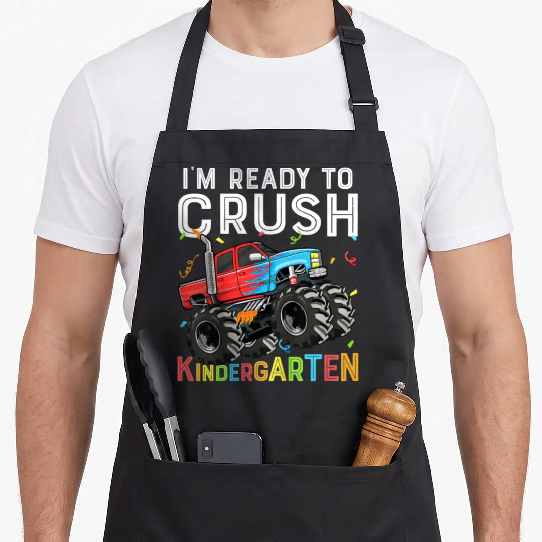 Occasion truck apron - Cartoon monster truck in red and blue surrounded by confetti with I'm Ready to Crush — shown on a black cotton canvas apron against a white background