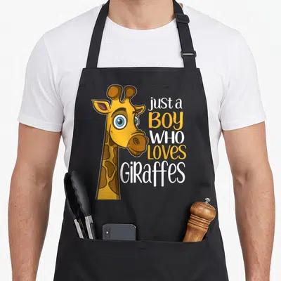 Retro giraffe apron - Cartoon giraffe head next to stacked text just a boy who loves giraffes in yellow and white — shown on a black cotton canvas apron against a white background
