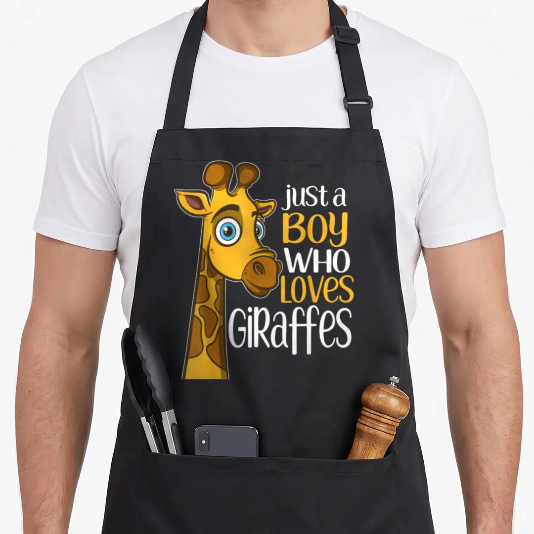 Retro giraffe apron - Cartoon giraffe head next to stacked text just a boy who loves giraffes in yellow and white — shown on a black cotton canvas apron against a white background