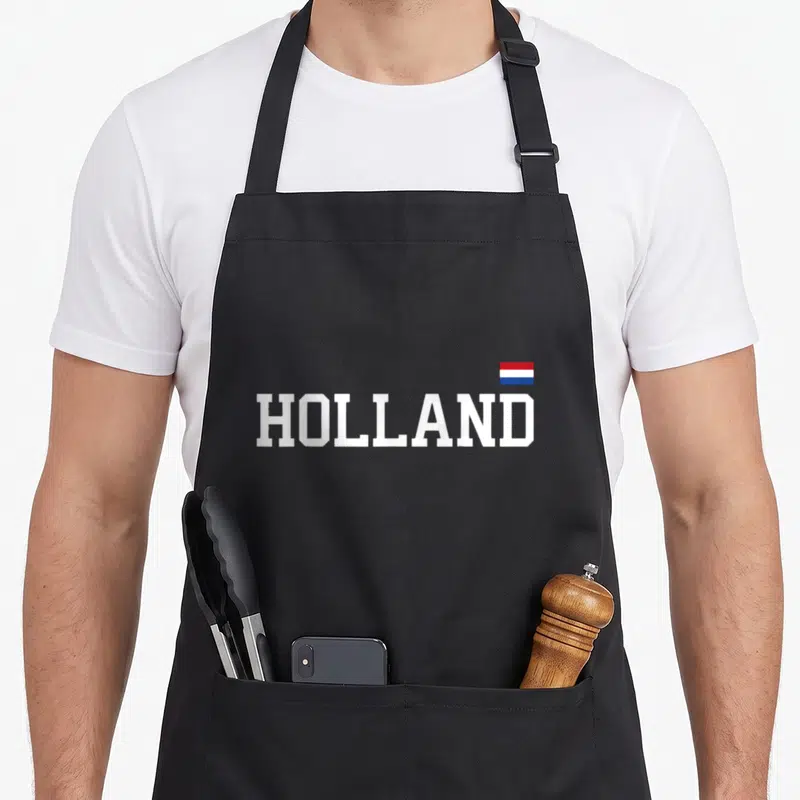 Holland netherland dutch aprons - White HOLLAND text with small red white blue flag above last letters — shown on a black cotton canvas apron against a white background
