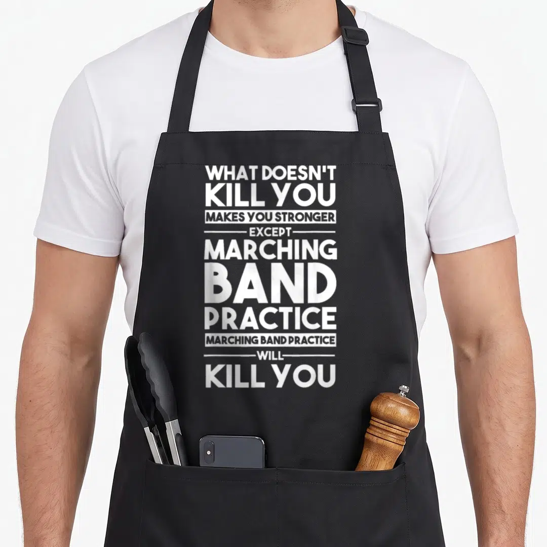 Kill marching band apron - White stacked text reading what doesn't kill you makes you stronger except marching band — shown on a black cotton canvas apron against a white background