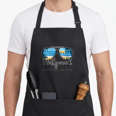 Hollywood beach tree apron - Sunglasses reflecting palm trees and yellow umbrella with Hollywood Florida Beach text — shown on a black cotton canvas apron against a white background