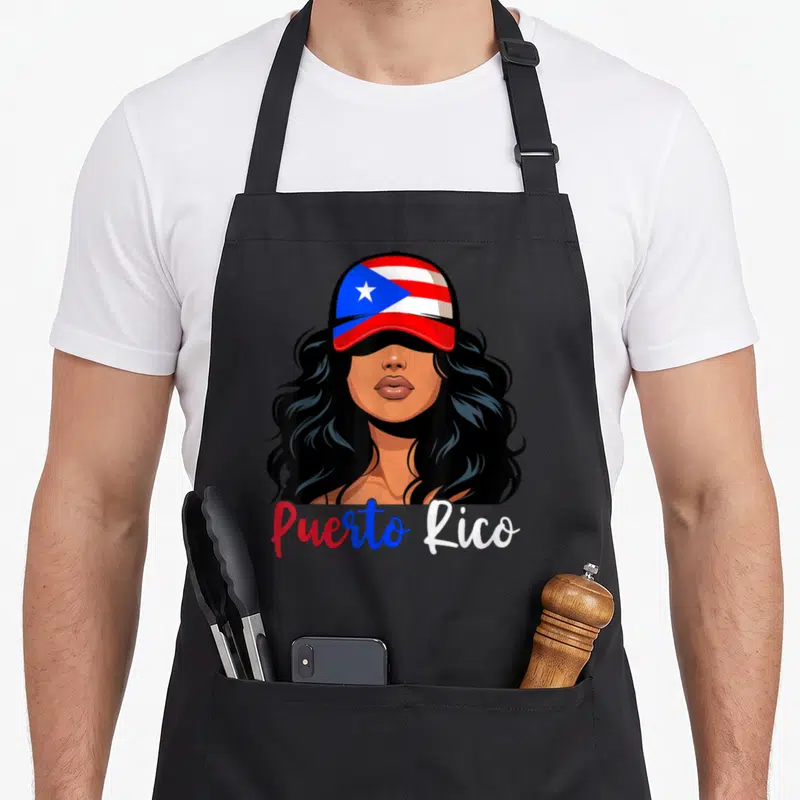 Rican puerto girl apron - Cartoon woman in red white blue cap with Puerto Rico script text — shown on a black cotton canvas apron against a white background