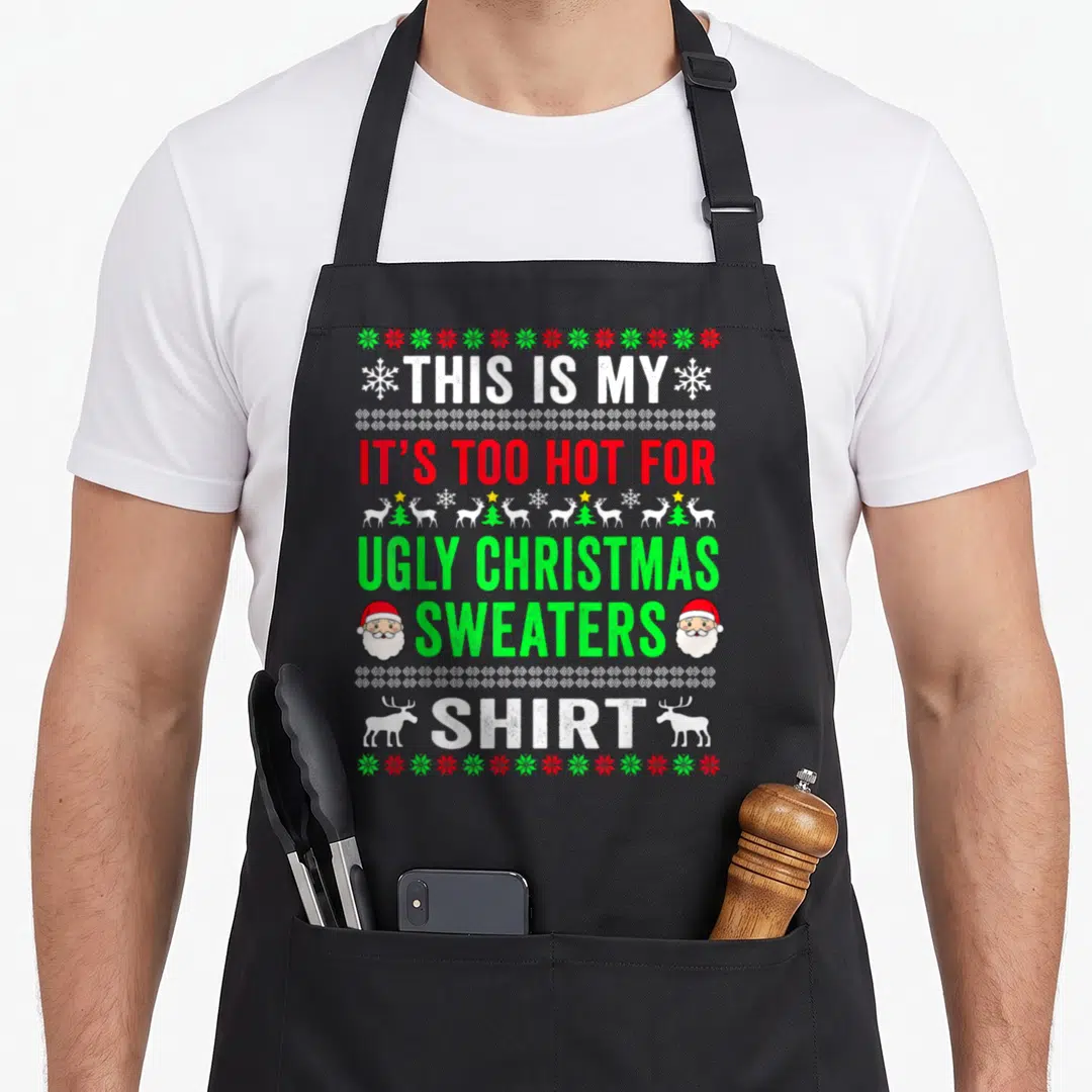 Funny hot ugly christmas apron - Stacked text reading THIS IS MY IT'S TOO HOT FOR UGLY CHRISTMAS SWEATERS SHIRT flanked — shown on a black cotton canvas apron against a white background