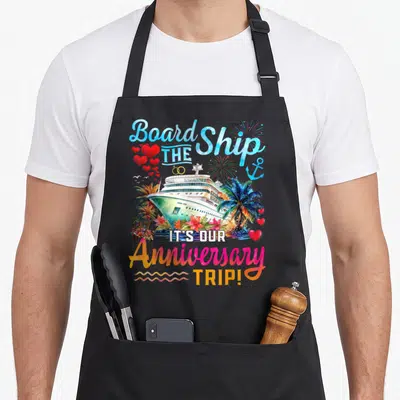 Our couple apron - Watercolor cruise ship with hearts, palm trees, and anniversary trip text — shown on a black cotton canvas apron against a white background