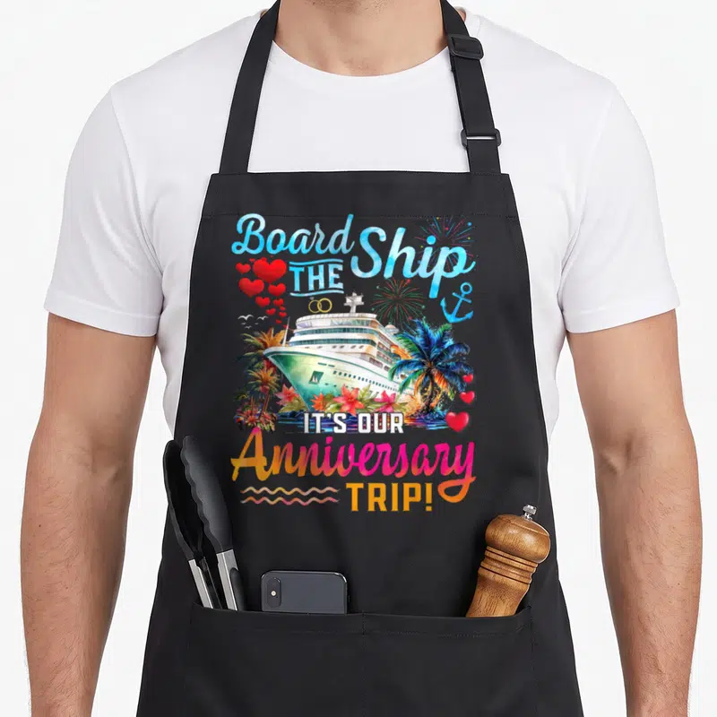 Our couple apron - Watercolor cruise ship with hearts, palm trees, and anniversary trip text — shown on a black cotton canvas apron against a white background