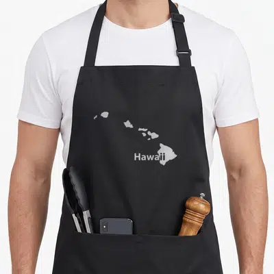Hawaii map pride apron - Grey silhouette map of Hawaii islands with text overlapping the largest island — shown on a black cotton canvas apron against a white background