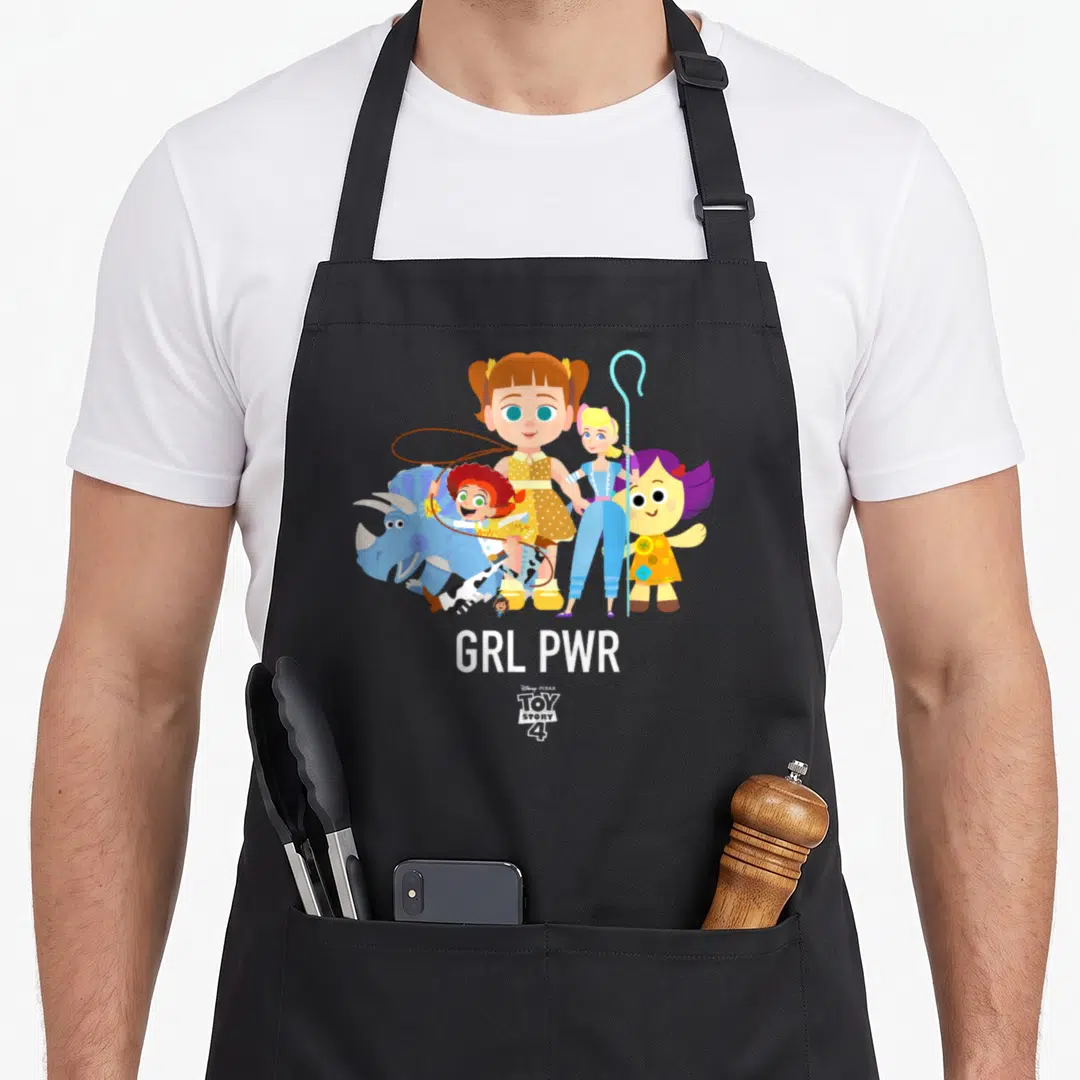 Grl camping apron - Female toy characters standing with GRL PWR text in yellow blue white purple — shown on a black cotton canvas apron against a white background