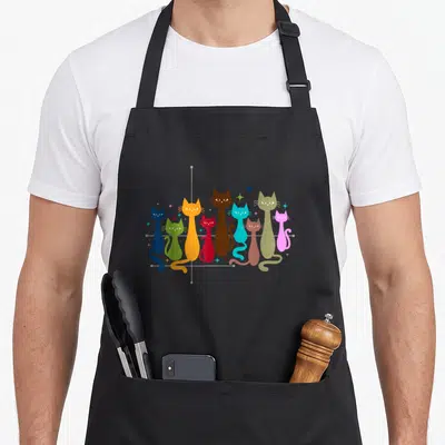 Kitten artwork cat apron - Nine stylized cats in blue green orange red brown and pink on grey grid with stars — shown on a black cotton canvas apron against a white background