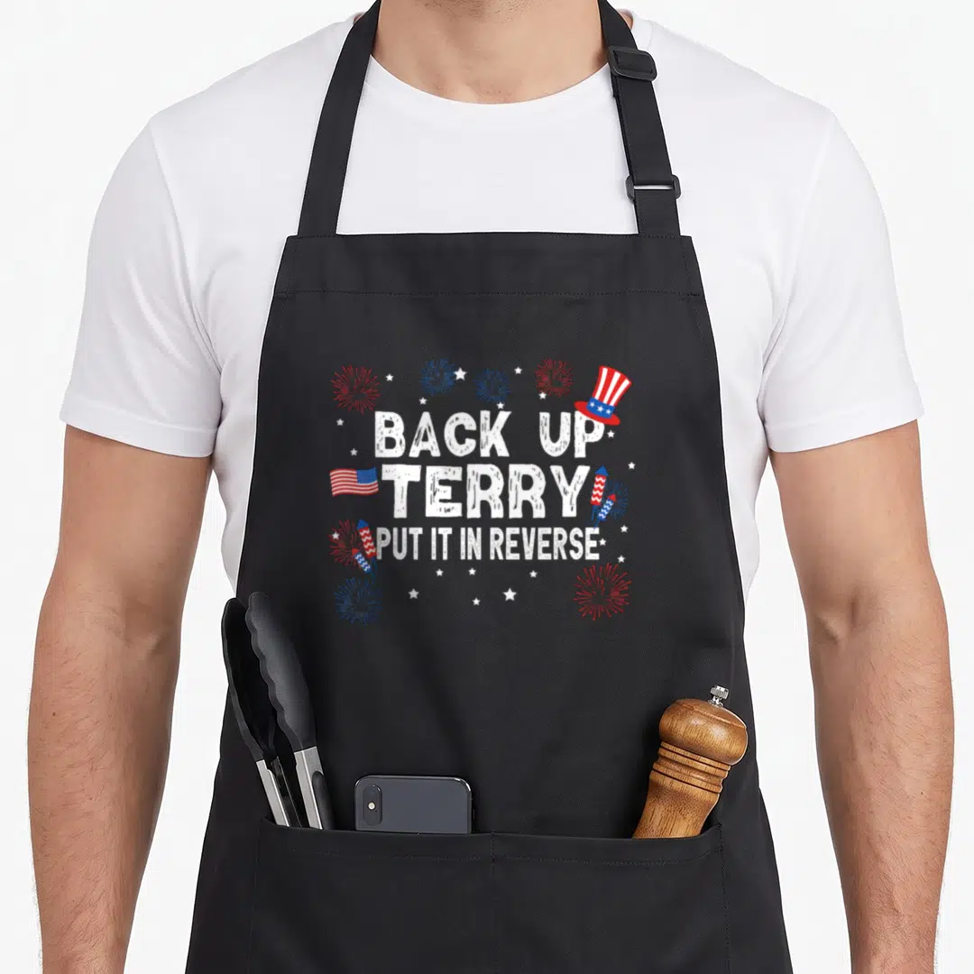 Terry reverse 4th of july apron - Back Up Terry Put It In Reverse text with Uncle Sam hat, flag, and fireworks — shown on a black cotton canvas apron against a white background
