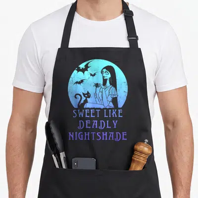 Sally meh apron - Blue circle with woman cat bats and text Sweet Like Deadly Nightshade — shown on a black cotton canvas apron against a white background