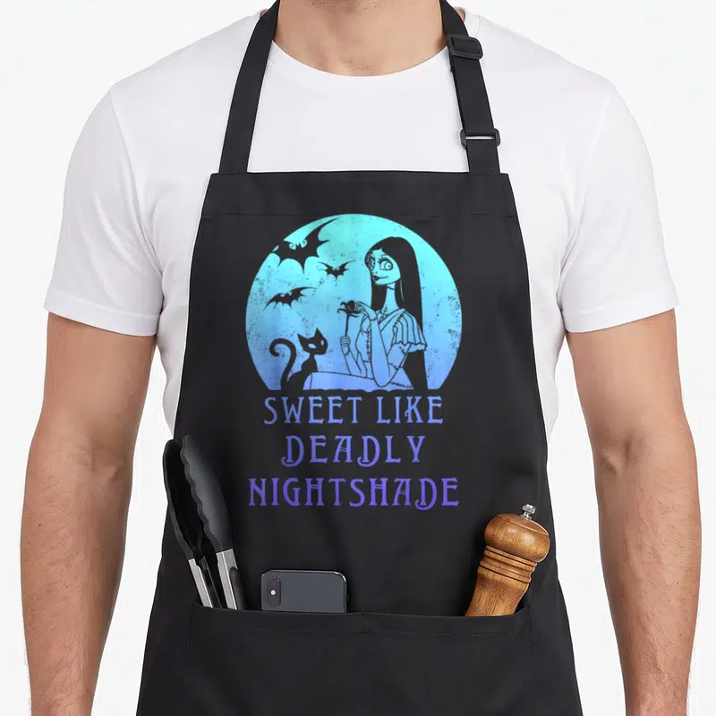 Sally meh apron - Blue circle with woman cat bats and text Sweet Like Deadly Nightshade — shown on a black cotton canvas apron against a white background