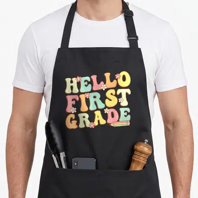 Hello grade cute teacher aprons - Hello First Grade pastel text with flowers and pencil illustration — shown on a black cotton canvas apron against a white background