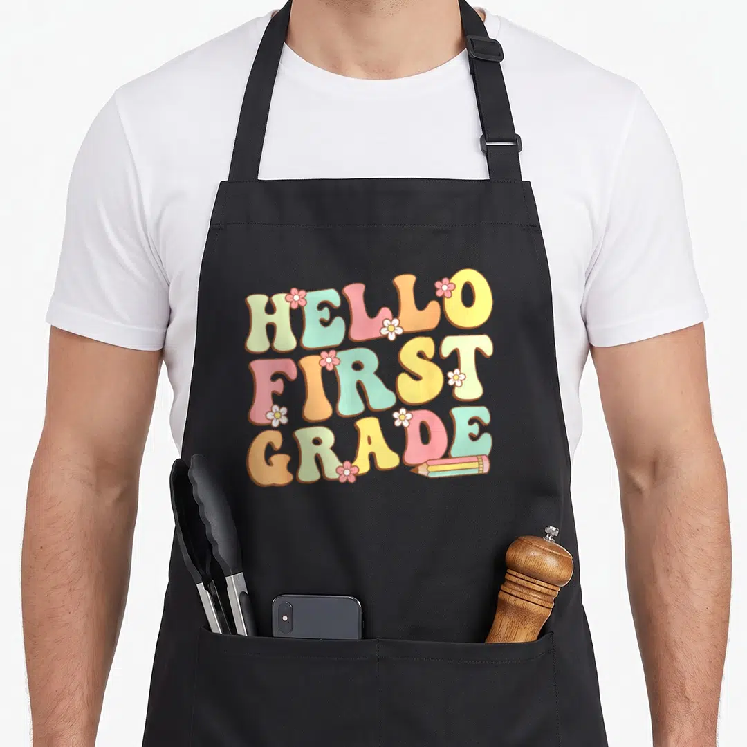 Hello grade cute teacher aprons - Hello First Grade pastel text with flowers and pencil illustration — shown on a black cotton canvas apron against a white background