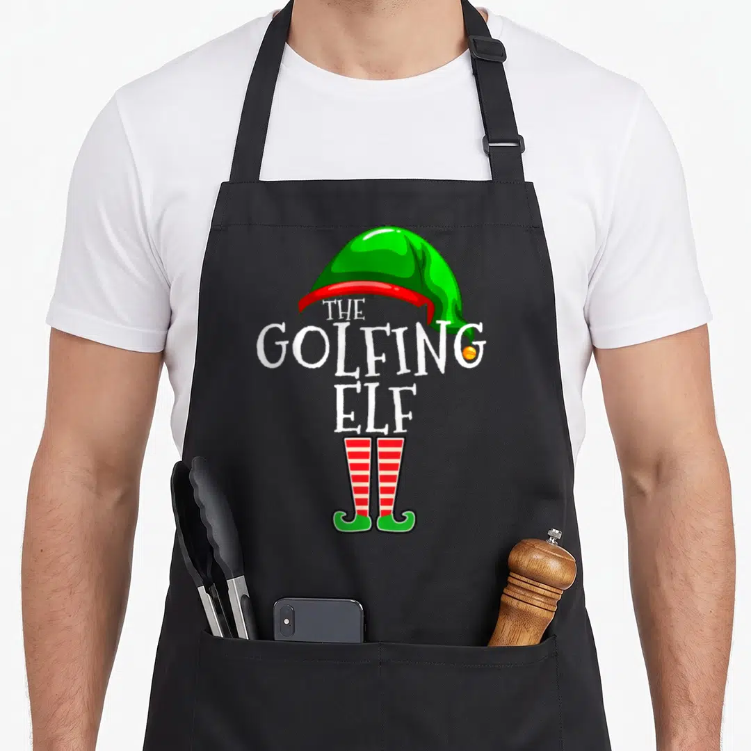 Golfing christmas elf apron - Stacked THE GOLFING ELF text with green hat and red striped legs — shown on a black cotton canvas apron against a white background