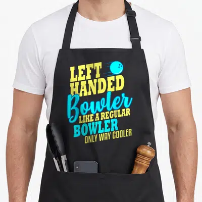 Bowling left apron - Yellow and blue stacked text reading left handed bowler with moving ball graphic — shown on a black cotton canvas apron against a white background