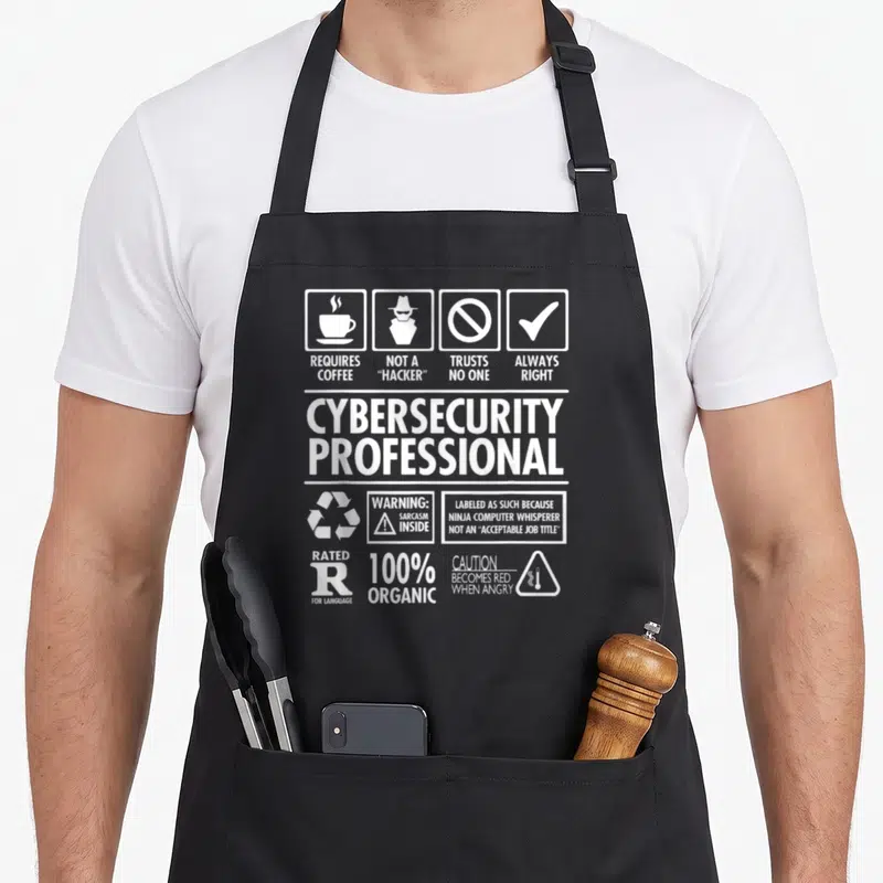 Nerdshizzle professional aprons - White typography design listing cybersecurity traits like requires coffee and not — shown on a black cotton canvas apron against a white background