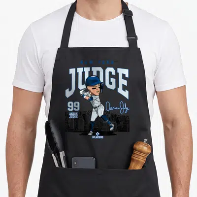 Mlbjud3005w new york apron - Cartoon baseball player JUDGE 99 with signature and skyline in blue white grey — shown on a black cotton canvas apron against a white background