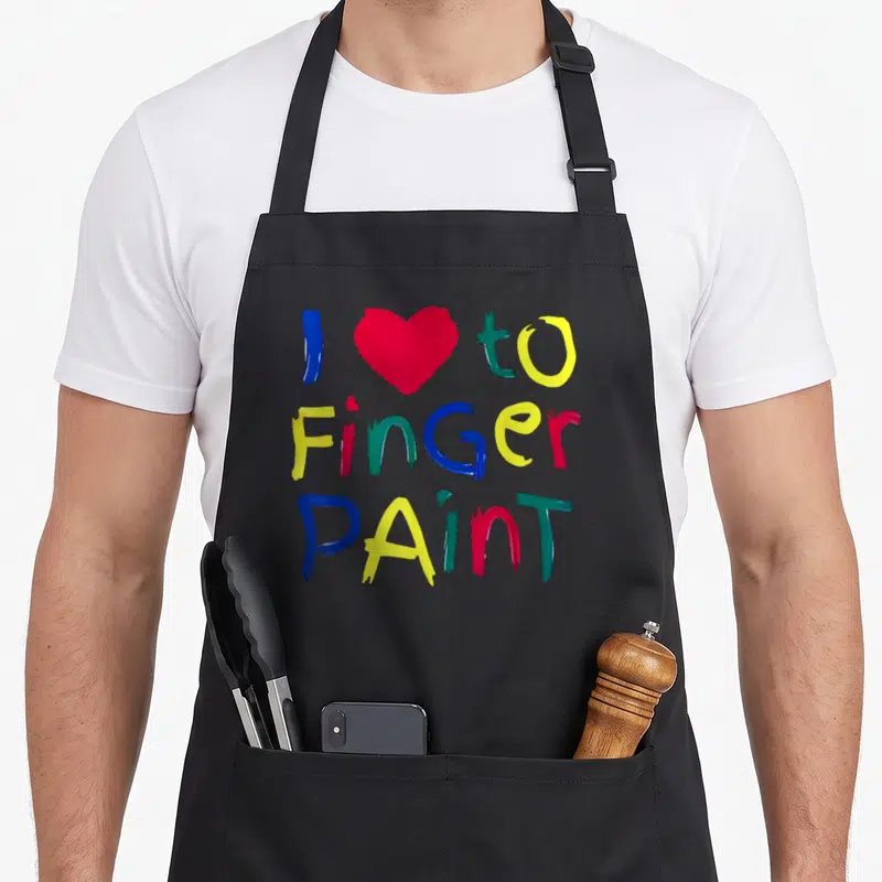 Finger valentine apron - I to Finger Paint text with red heart and multi-colored finger-style lettering — shown on a black cotton canvas apron against a white background