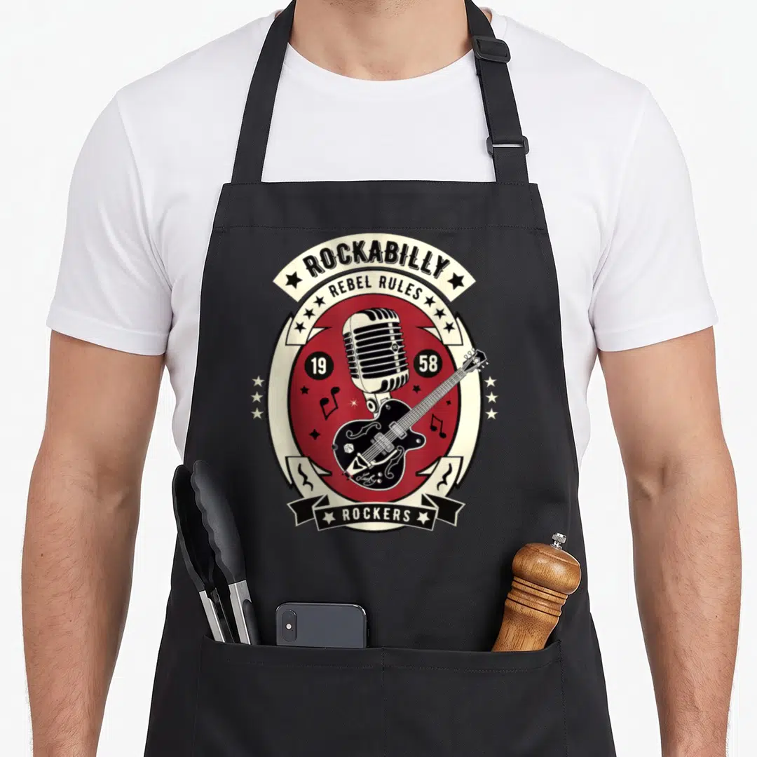 Rocker rockabilly apron - Vintage 1958 emblem with microphone, guitar, and Rebel Rules text in red and cream — shown on a black cotton canvas apron against a white background