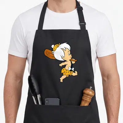 Bamm flint apron - Cartoon caveman child running with club in yellow brown and tan — shown on a black cotton canvas apron against a white background