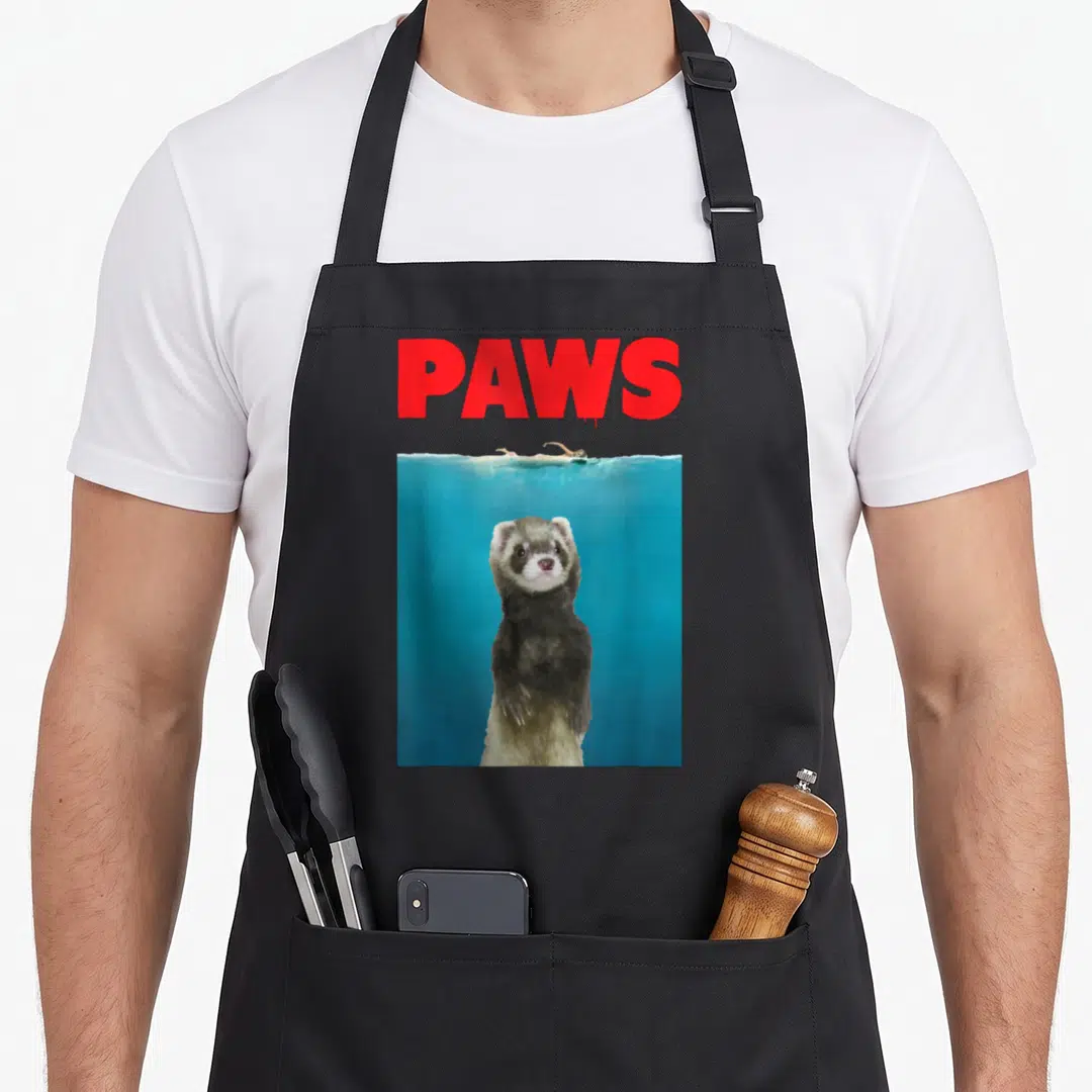Paw ferret lover apron - Red PAWS text above a ferret standing underwater with a swimmer on the surface — shown on a black cotton canvas apron against a white background